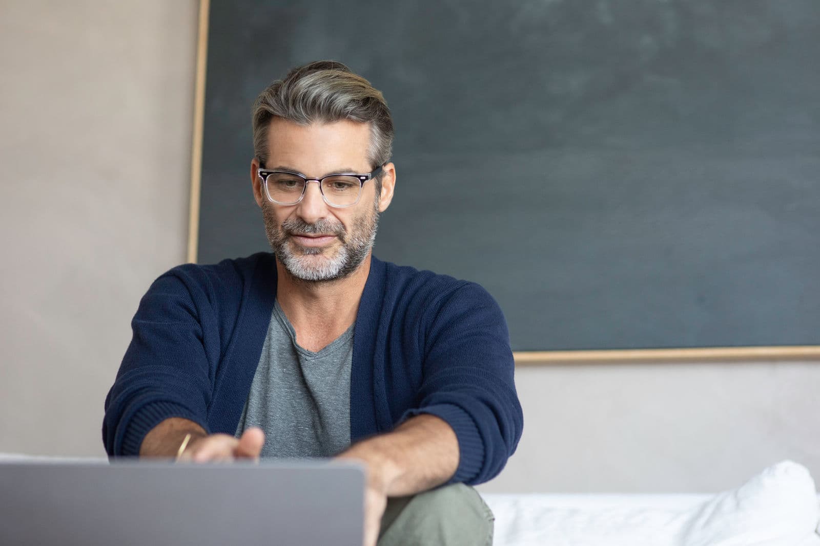 Jim Curtis working at a laptop, glasses on, a chalkboard behind him